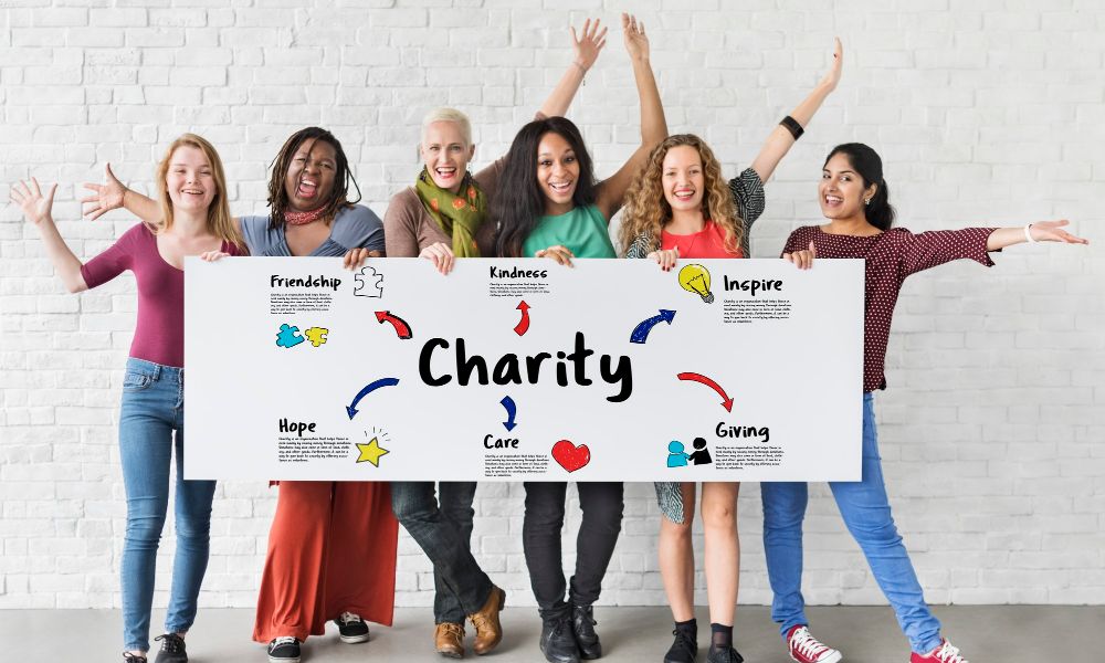 A group of smiling healthy people holding the banner which reads charity