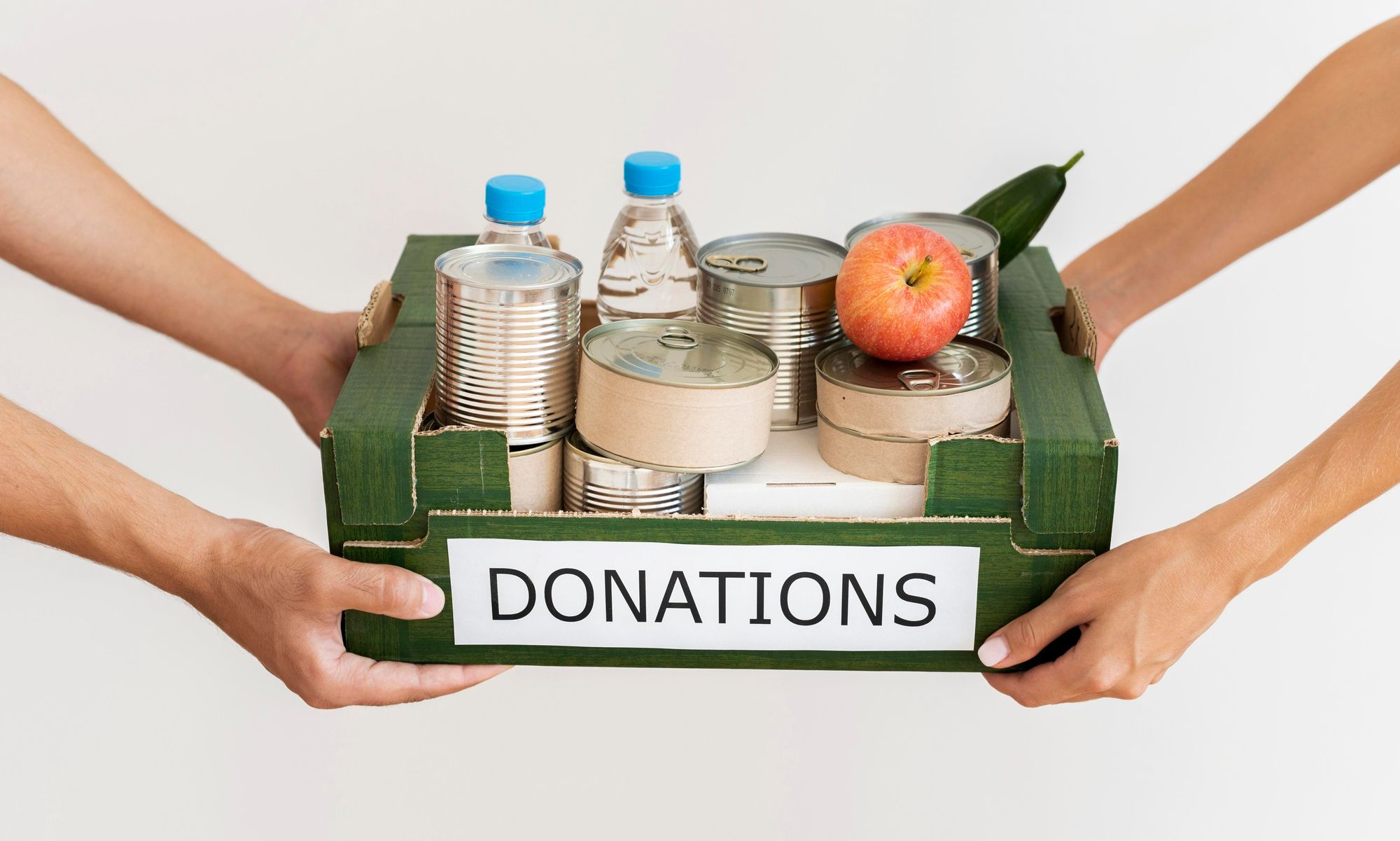 Image of one person giving many cans inside a half open box which has donations written on it to another person